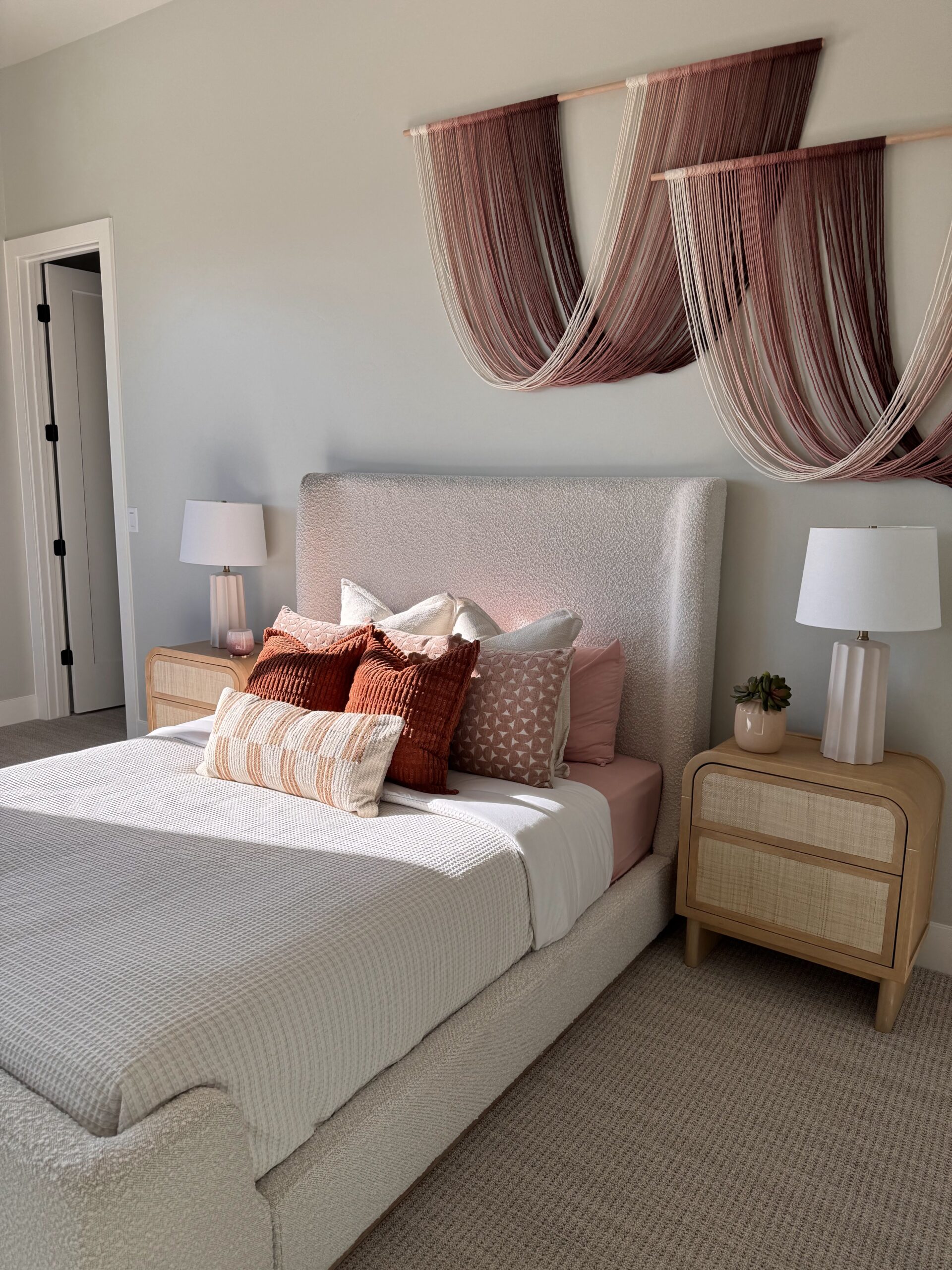 Professionally staged bedroom in Southern Utah featuring warm neutral decor, layered pillows, and modern bedside tables