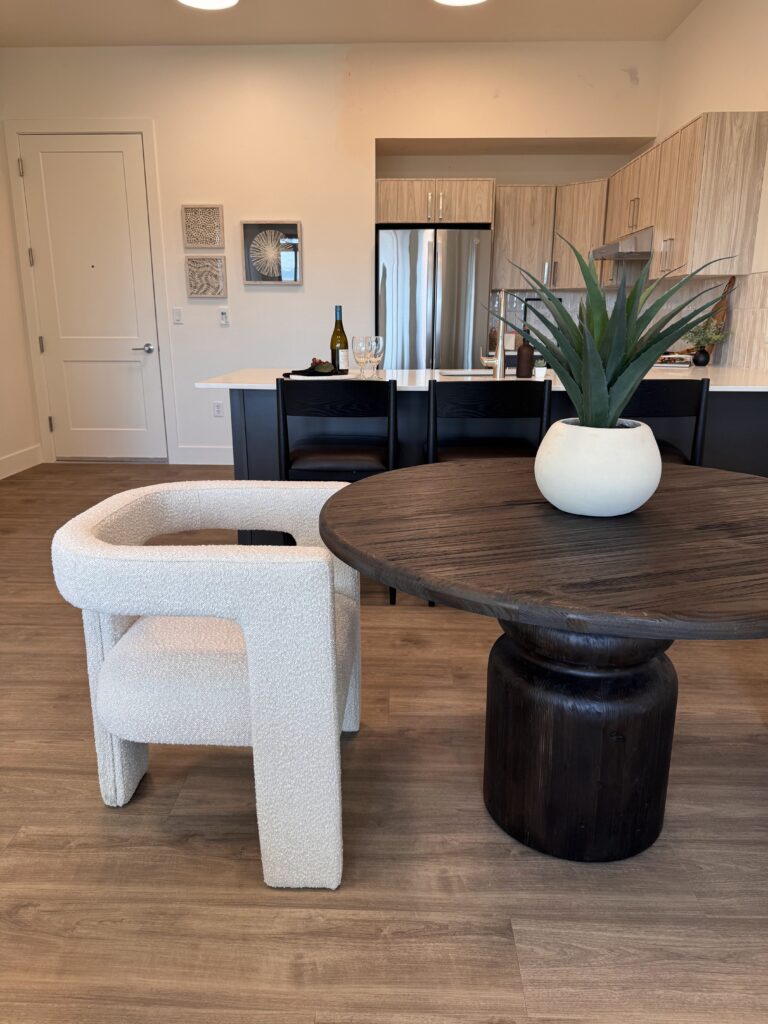 Professional home staging in Southern Utah featuring a round dining table, boucle accent chair, and open kitchen layout