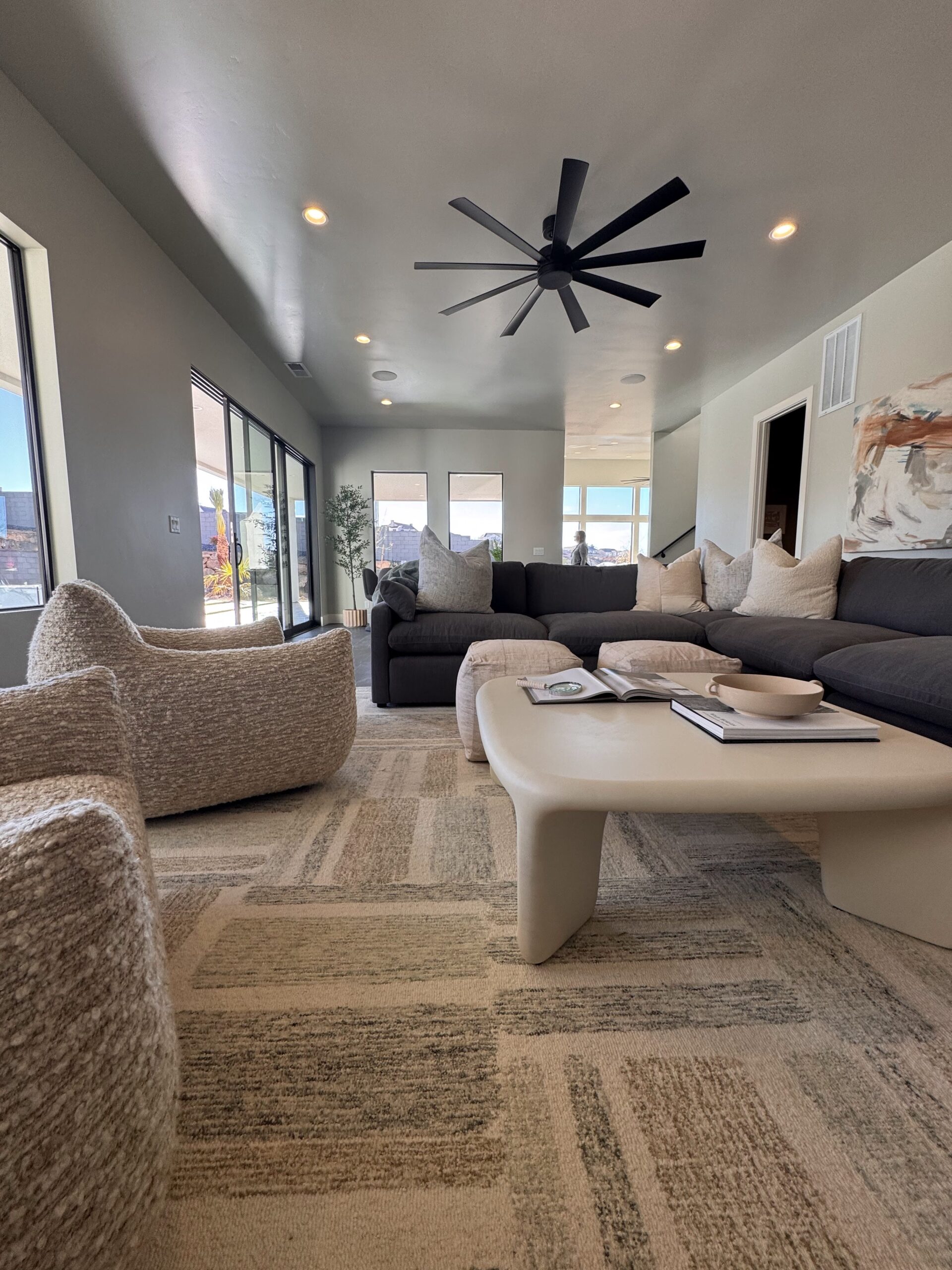 Professional home staging in Southern Utah showing open concept living room with sectional sofa, neutral decor, and large windows