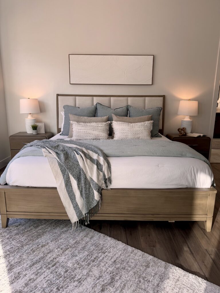 Professional home staging in Southern Utah showing a primary bedroom with layered bedding, symmetrical nightstands, and neutral styling
