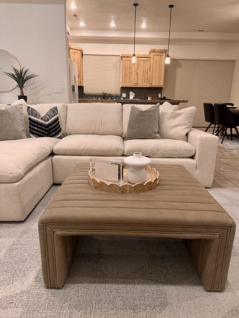 Luxury professionally staged open concept living room in Southern Utah featuring sectional sofa, designer coffee table ottoman, and model-home style decor